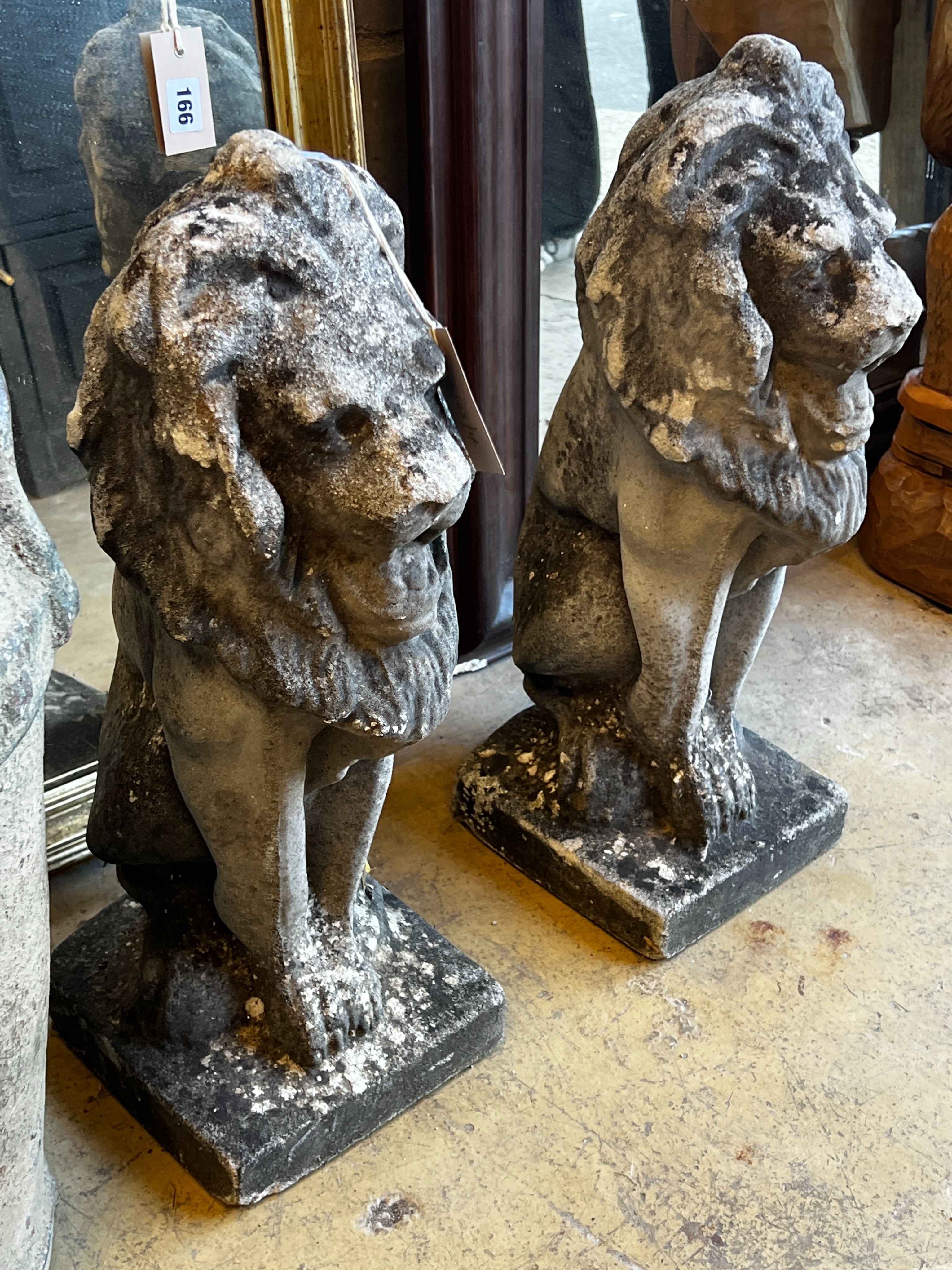 A pair of reconstituted stone seated lion garden ornaments, height 55cm